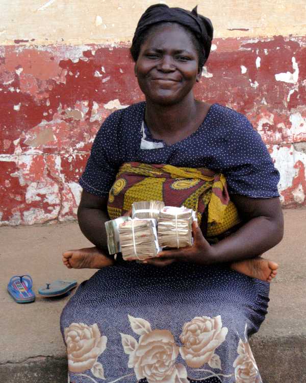 african microentrepreneur holding money with a baby on her back