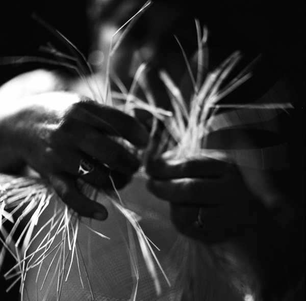 close up of hands weaving panama hat